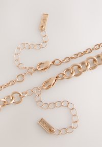 Two gold chain necklaces with lobster clasps and adjustable links on a plain light background.