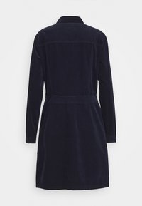 Abito in velluto a coste blu navy con maniche lunghe, colletto, lunghezza intermedia e una cintura in vita; presenta cuciture visibili e uno yoke.