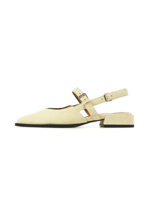 Beige suede flat shoe with pointed toe, low block heel, and double buckle straps across instep and around heel.