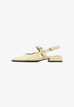 Beige suede flat shoe with pointed toe, low block heel, and double buckle straps across instep and around heel.
