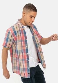 Korte mouwen geblokte overhemd in rood, blauw en beige tinten; heeft een knoopsluiting, een relaxte pasvorm en een contrasterend wit onderhemd eronder.