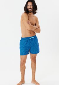 Blårandiga badshorts med elastisk midja och turkos dragsko. Slätt tyg, knälång skärning och utan fickor.