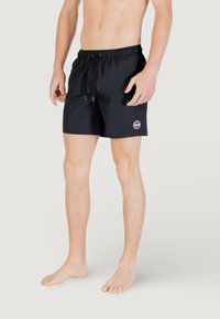 Shorts da bagno neri con cintura elastica e stringi vita. Presentano un piccolo logo circolare sulla gamba sinistra. Tessuto morbido e leggero.