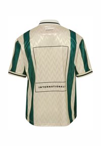 Beige sportstrøye med grønne vertikale striper, svart kant på ermer og krage, teksten "INTERNATIONALS" og Hummel Sportswear-logo på baksiden.