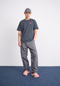 Gray T-shirt with rose logo, gray cargo pants, and pink sneakers. The hat is light gray with eyelets. All items feature a casual design.