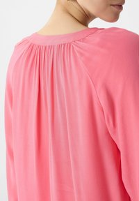 Langärmlige, leuchtend pinke Bluse mit einer plissierten Applikation am hinteren Halsausschnitt und aus glattem, leichtem Stoff in entspannter Passform.