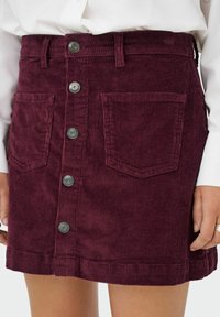 Skirt od bordo kordura visoka u struku s prednjim gumbima, dva prednja džepa, nosi se s dugim bijelim topom.