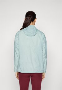 Light green checked jacket with a hood, long sleeves, soft texture, and a relaxed fit, paired with burgundy fitted leggings.