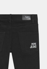 Černé džíny s koženou etikettou s vyraženým nápisem "Pepe Jeans" na pásku, dvěma zadními kapsami s bílým vyšitým logem.