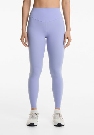 Leggings taille haute violet clair avec un design sans couture et une texture lisse, associés à des chaussures de sport de couleur claire.