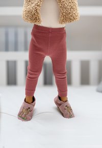 Roze geribbelde legging in combinatie met roze slippers met een ontwerp van een bruine bok. Zachte textuur en een snug fit, geplaatst tegen een lichte achtergrond.