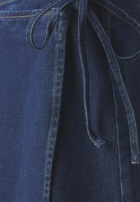 Mörkblå denimtyg med en slät yta, som har en knytning vid midjan och synliga sömmar längs kanterna.