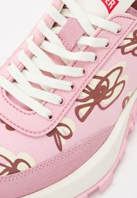 Pink sneaker with a textured fabric upper, featuring white laces and brown floral patterns, complemented by a white sole and pink accents.