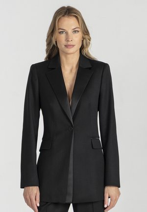 Czarny, dopasowany blezer wykonany z gładkiej tkaniny z satynowym kołnierzem. Posiada jedno zapięcie na guzik oraz dwie przednie kieszenie, tworząc elegancką sylwetkę.