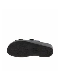 Suela de zapato negra con un patrón de agarre texturizado, bordes suaves y una ligera curvatura. Diseñada con un material de goma resistente.