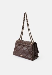 Mørkebrun quiltet læderhåndtaske med guldkæde-strop og lille gylden Steve Madden-logo på forsiden, sat mod hvid baggrund.