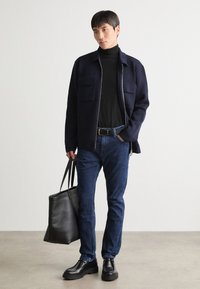 Mornarica jakna s zadrgo, črn pulover, modri kavbojke, črne čevlje in črna torba. Dva žepa na prsih jakne. Gladke teksture.