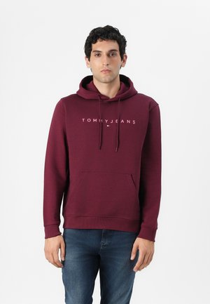 Felpa maroon con tasca anteriore e cappuccio con cordino. Presenta il logo "TOMMYJEANS" in bianco sul petto. Tessuto morbido e texture piacevole.