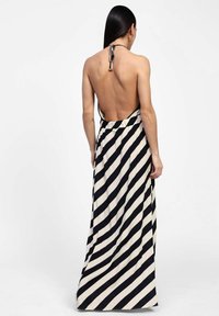Abito maxi a halter a righe nere e crema con schiena scoperta, caratterizzato da una vita arricciata e un tessuto morbido e leggero.