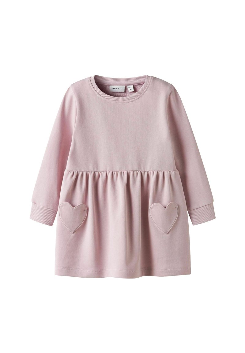 Robe rose à manches longues avec une taille froncée, dotée de deux poches en forme de cœur et d'un col rond. Fabriquée en coton doux.