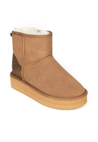 Bota de ante marrón claro con un suave forro de piel sintética, suela plana de goma color topo y un acento brillante en el talón. Altura a media pantorrilla.