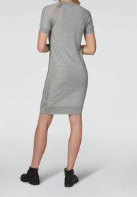 Robe en tricot grise à manches courtes, coupe ajustée et ourlet côtelé. Associée à des bottines noires à talons bas avec un design perforé.