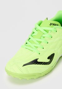 Zapatilla deportiva de color verde neón con logo negro, parte superior de malla, cordones atados y suela texturizada, diseñada para deportes o running.