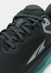 Must musta mustreid ja teal jooksujalats, millel on võrgust ülemine osa, peegeldavad aktsendid ja paelad. Omab brändi silti, millel on tekst "Torin 8 GORE-TEX." Tekstuurilised detailid.