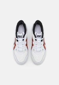 Ett par vita ASICS-sneakers med svart foder och orange ränder, sedd uppifrån på en ren vit bakgrund.