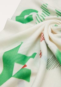 Biały szal z tkaniny z zielonym abstrakcyjnym wzorem i akcentami w kolorze czerwonym oraz niebieskim, o teksturowanym splocie i miękkim układzie.