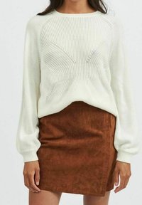 White knitted sweater with textured pattern and puffed sleeves, paired with a brown faux suede mini skirt with a diagonal seam.
