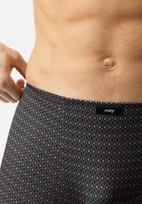 Tmavé vzorované boxerky s geometrickým designem v červené a zelené barvě, vyrobené z měkké tkaniny, která poskytuje pohodlné nošení, a s elastickým pasem s logem.