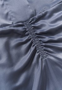 Tume tumesinine kangas, millel on kortsunud tekstuur ja elastsed detailid. Sile, läikiv pind, millel on peened valguse peegeldused.
