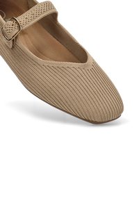 Zapato Mary Jane de punto beige con un exterior texturizado, punta cuadrada y correa ajustable con hebilla a lo largo del empeine. Forro interior suave.
