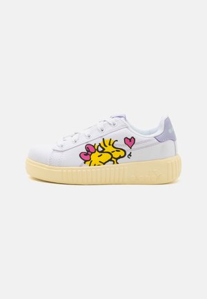 White canvas sneaker with yellow cartoon characters printed on the side, purple accents, and a ribbed beige sole. Lace-up design.