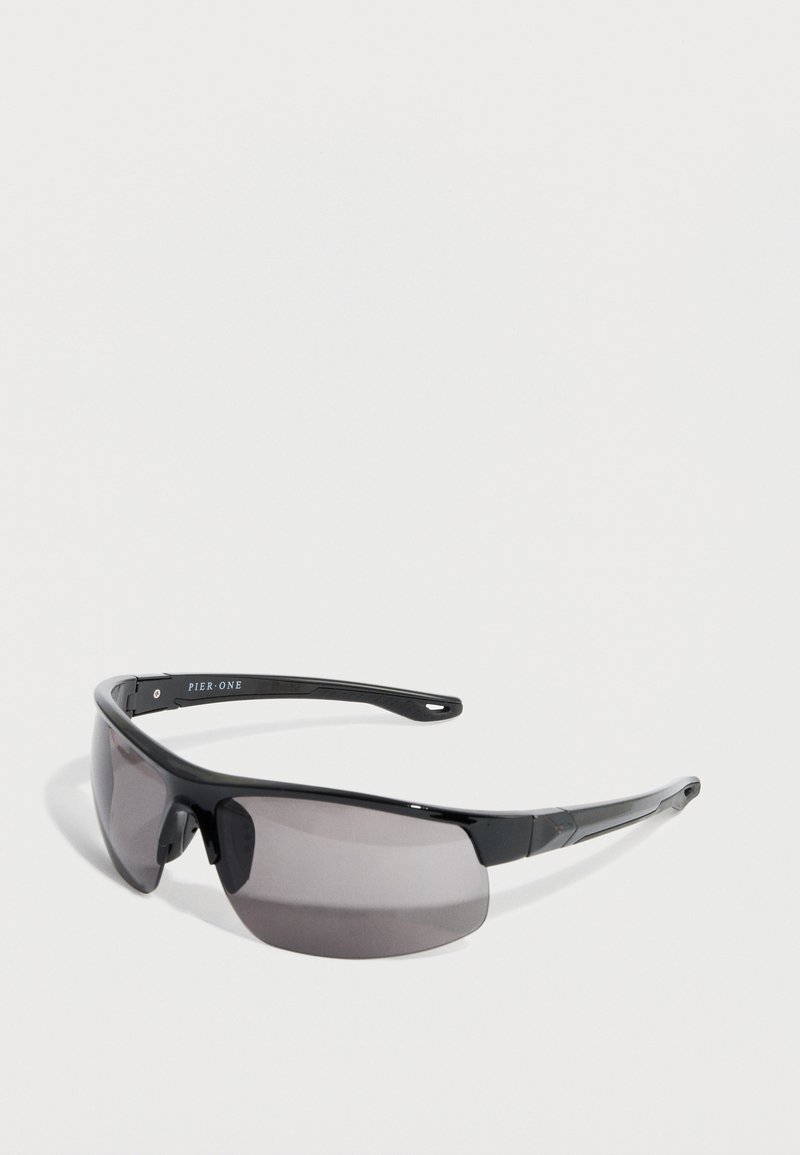 Μαύρα αθλητικά γυαλιά ηλίου με σχεδιασμό τύπου wraparound, γκρι φακούς με χρωματισμό, ανθεκτικό μαύρο σκελετό και χαραγμένο όνομα μάρκας στο βραχίονα.