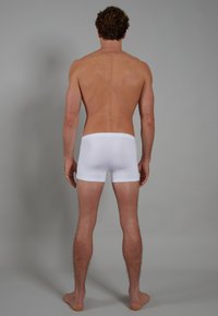 Weiße Baumwoll-Boxershorts mit glatter Textur, körpernaher Passform und bequemen Bund, von hinten vor einem grauen Hintergrund präsentiert.
