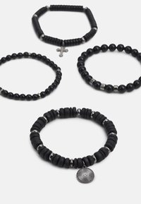 Sett med fire svarte armbånd med varierte perleformer og -størrelser, med metalletterfyllinger og et charmsdekor på ett armbånd.