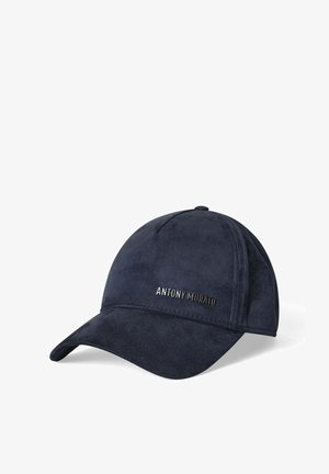 Marineblauwe suède pet met een gebogen klep en een metalen merklogo aan de voorkant. Voorzien van gestikte accenten en een ronde kroon.