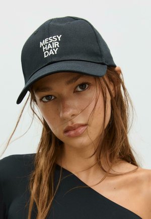Mustaparta, jossa on valkoisella brodeerattu "MESSY HAIR DAY", rakenteellinen kruunu ja kaareva lippa, valmistettu sileästä kankaasta.