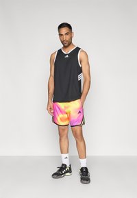 Čierny atletický top bez rukávov s bielymi detailmi, doplnený o živé ružové a oranžové šortky s prechodom farieb, čiernymi pruhmi a logom.