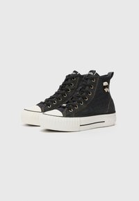 Sneakers alte in denim nero con punte in gomma bianca, occhielli in metallo dorato e logo distintivo sulla caviglia.