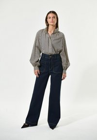 Gestreifte Knopfhemd mit Kragen, kombiniert mit hochtaillierten, weiten dunkelblauen Jeans aus Denim mit Akzentnähten und vorderen Taschen.