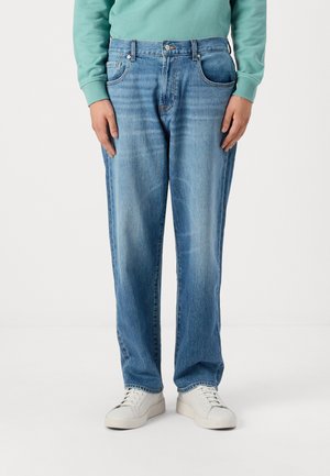 Light blue denim jeans with a relaxed fit, featuring front pockets, a zipper fly, and subtle fading. Paired with white sneakers.