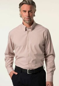 Heren overhemd met knoopsluiting in lichtroze met witte verticale strepen. Voorzien van een kraag, lange mouwen en een slim fit ontwerp, gecombineerd met een donkere broek.