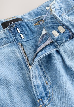 Világoskék farmernadrág cipzáras behúzóval, ezüst színű fémrészekkel és kétgombos záródással. Eltérést mutató mosott hatás és látható varrásrészletek jellemzik.