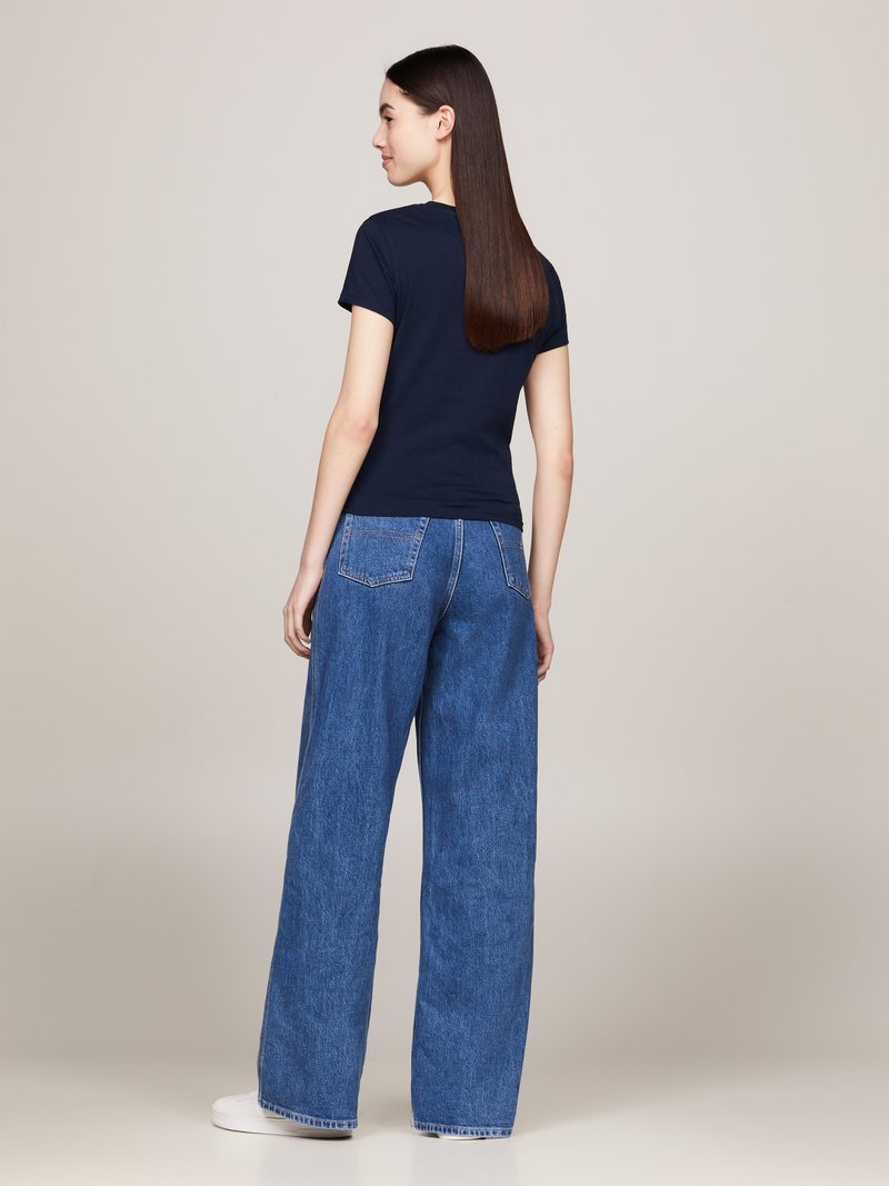 Camiseta de marina de manga corta combinada con jeans de denim azul de pierna ancha de talle alto. Tejido suave con un corte relajado. Zapatos blancos.