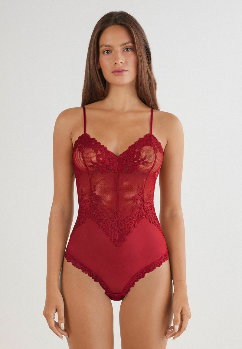Roter Spitzenbodysuit mit einem transparenten Mesh-Frontbereich, der mit floralem Stickereimuster verziert ist, verstellbaren dünnen Trägern und einem unteren Teil aus festem Stoff mit Spitzenbesatz.