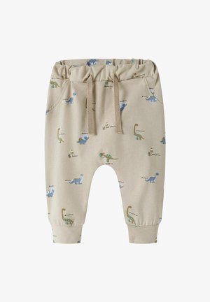 Pantalon beige pour tout-petit avec taille élastique, cordon de serrage, et illustrations de dinosaures bleus et bruns dispersées sur le tissu.