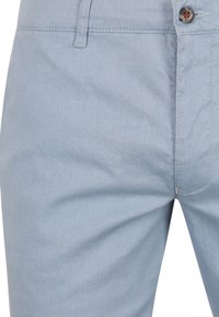 Hellblaue Baumwollchinos mit strukturierter Oberfläche. Verfügt über einen einzigen Knopfverschluss und Gürtelschlaufen am Bund.